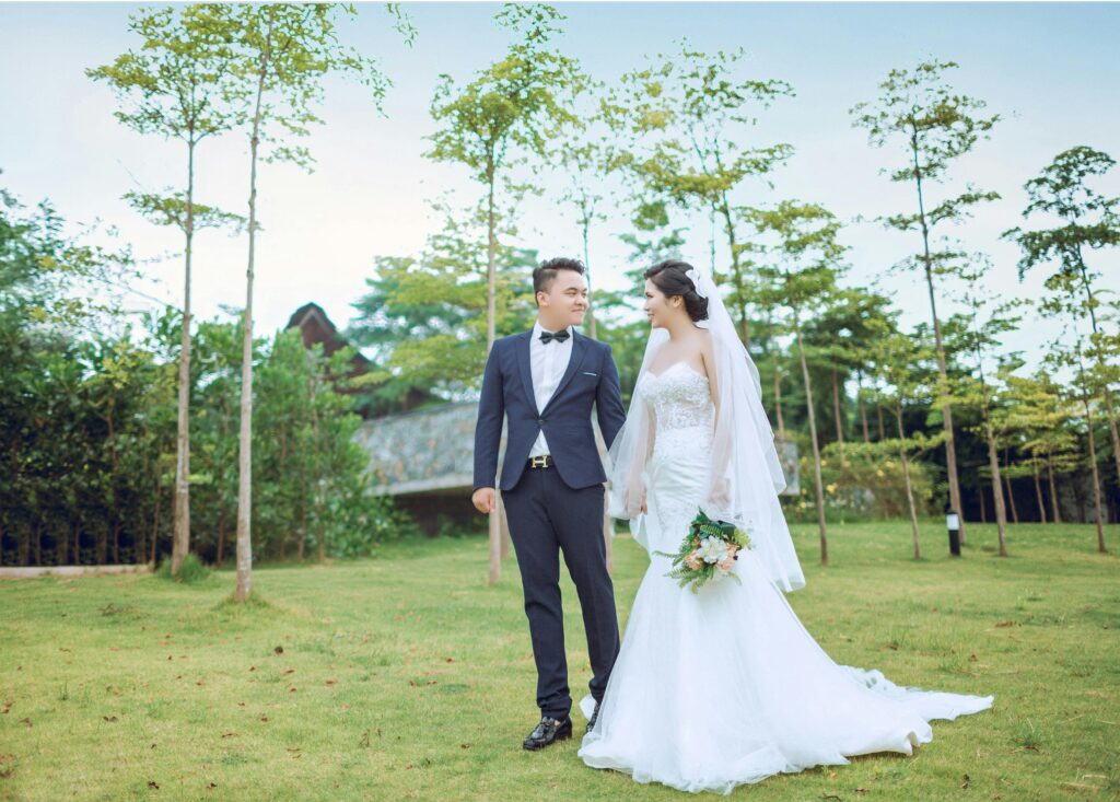 A romantic couple enjoying their wedding day, elegantly dressed, in a beautiful park setting.